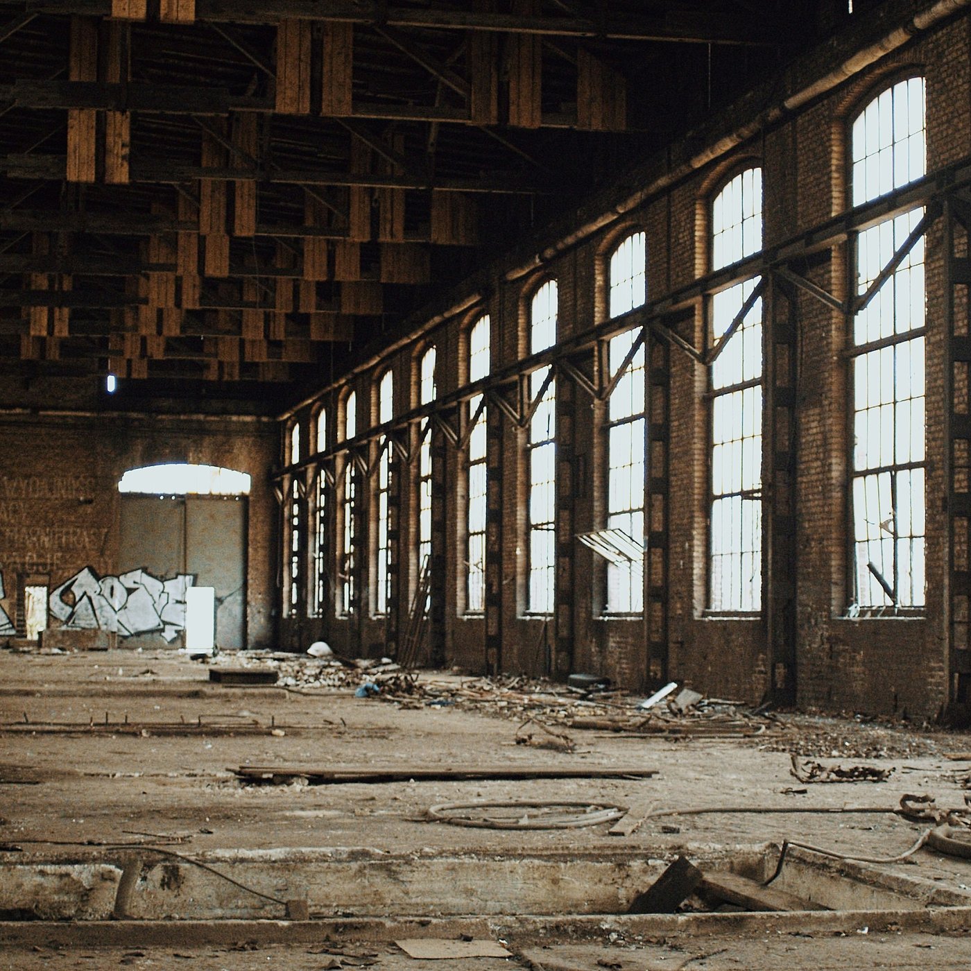 The Reclaimers — a novel by Kyle Castro. An abandoned factory hall, light falling through broken windows.